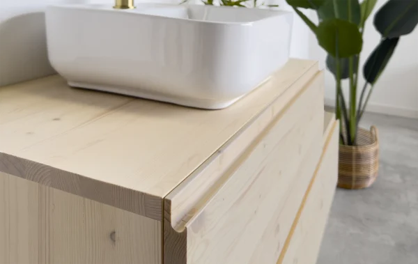 Mueble de baño de madera maciza con nudos color natural. Sistema de apertura de cajón con uñeros que se mimetiza con el mueble.