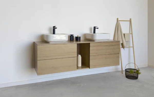 Mueble de baño en madera maciza de roble natural. Cuenta con cuatro cajones amplios y un hueco central abierto, perfecto para añadir un toque decorativo y personal a tu espacio.